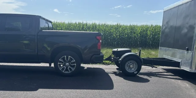 Half-ton pickup towing an enclosed cargo trailer with a Trailer Toad