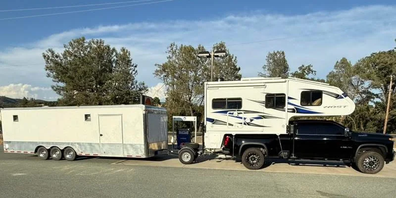 Truck camper towing a triple-axle enclosed trailer with a Trailer Toad